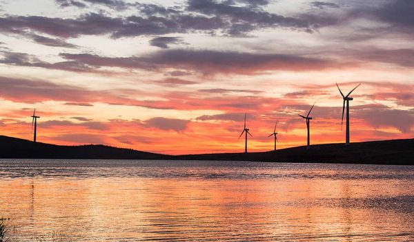 Wind turbines with a lake in front at sunset