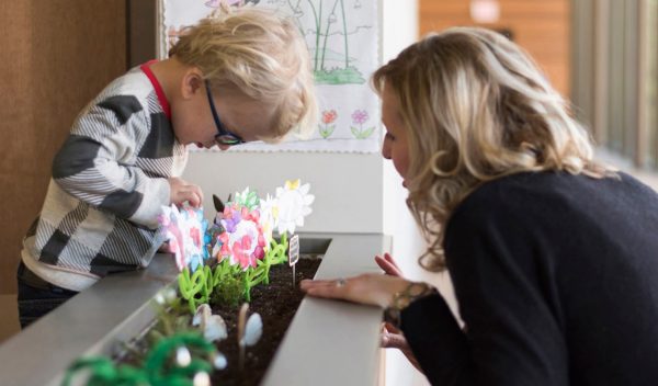 A woman with a child looking at plants in a classroom