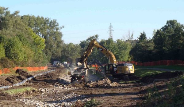 Excavator working next to gravity bypass pipe installed at stream restoration project.