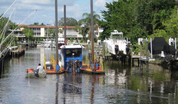 hydraulic dredge removes sediments within a residential canal