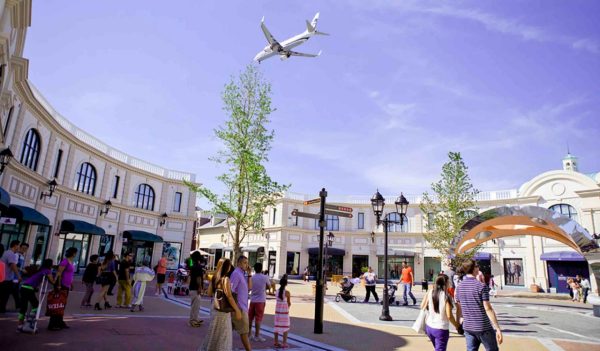 Plane flying over outdoor shopping area