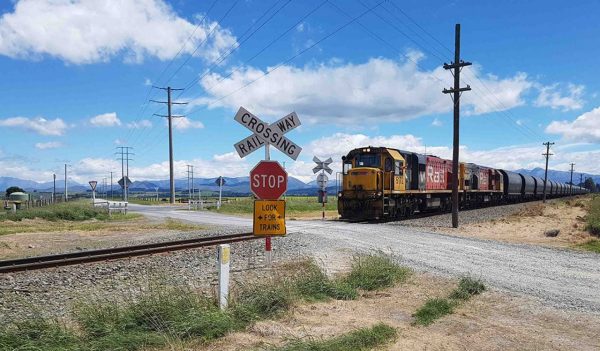 Rural railroad crossing with an train passing through. 