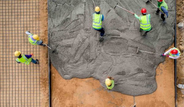 Construction workers pouring a wet concrete at road construction site
