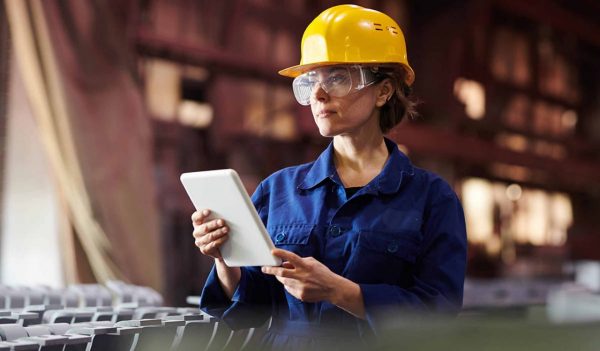 Waist up portrait of female worker using digital tablet while supervising production at plant