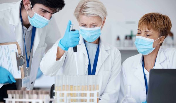 Analysis, covid team and employees in a lab for healthcare research, medical analytics or science. Chemistry, education and scientists witth face mask and teamwork to study a liquid or chemical.