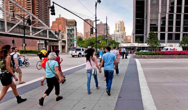 People walking down newly created pedestrian sidewalk alongside a new bike lane.